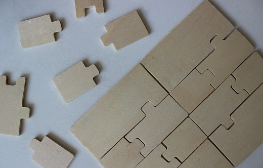 Wooden puzzle parts fitted to each other and separately on white surface