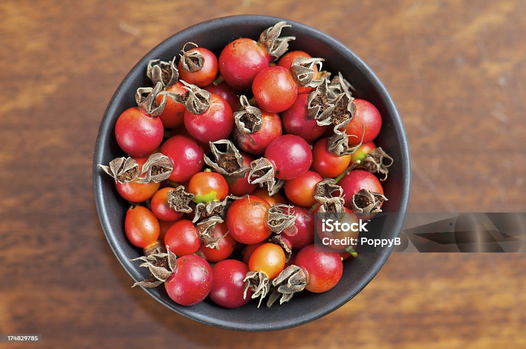 Black Bowl of Wild Rose Hips from Above Black bowl of freshly picked wild rose hips from above on wood Rose Hip Stock Photo