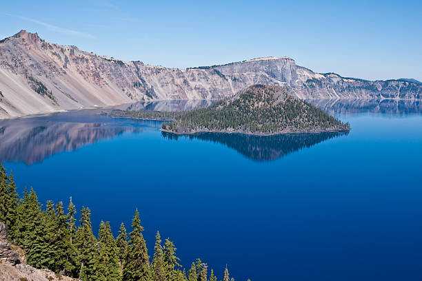 Crater Lake and Wizard Island Crater Lake exists in the blown-out caldera of a once mighty volcano known as Mount Mazama. This view of the lake and Wizard Island was taken from the Rim Trail in Crater Lake National Park, Oregon, USA. jeff goulden crater lake national park stock pictures, royalty-free photos & images