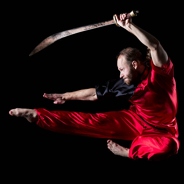 ушу борьбе с позиции с dao меч в midair - wushu skill action aggression стоковые фото и изображения