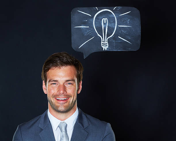 The ideas keep coming Portrait of a handsome businessman looking excited with a lightbulb drawn on the chalkboard above him man with a light bulb over his head stock pictures, royalty-free photos & images