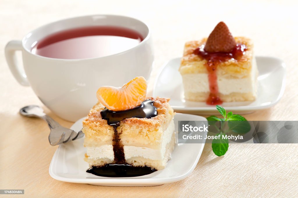 Cheesecakes with tangerine and strawberry Close up shot of a slice cheesecakes on small a plates decorated with tangerine and strawberry and cup of tea on background. Selective focus, shallow DOF. Slice of Cake Stock Photo