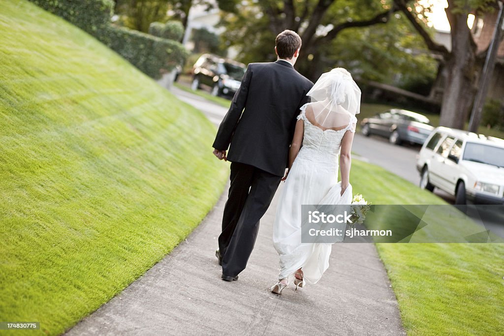 Coppia di sposi in partenza per luna di miele che tiene le mani - Foto stock royalty-free di Adulto