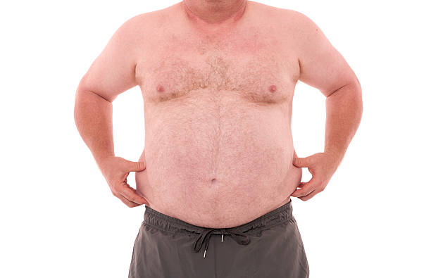 Over weight person. A front view of a over weight man pinching the sides of his stomach isolated on white. fat guy no shirt stock pictures, royalty-free photos & images