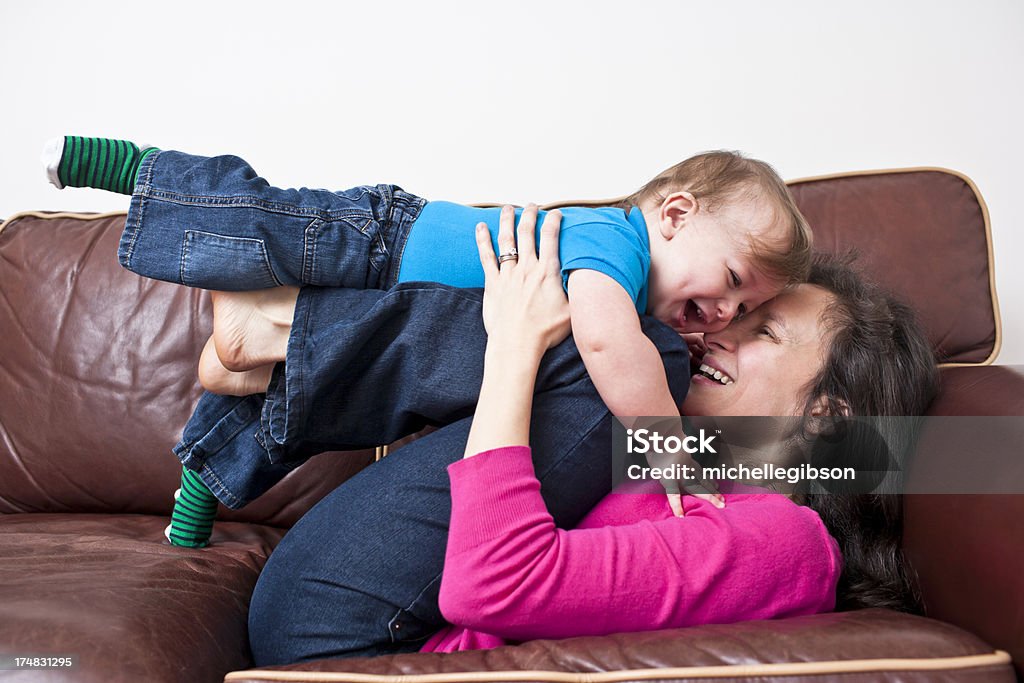 Risa madre y niño playtime en sofá de cuero - Foto de stock de 12-17 meses libre de derechos