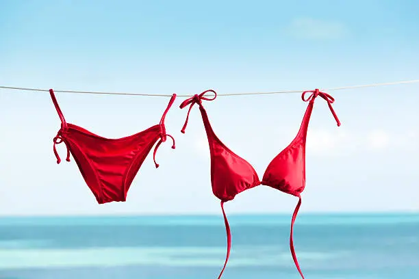 Subject: Bikini swimwear hanging on clothesline for drying, vacationing on tropical beach holiday.