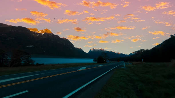 a vista de viagem de estrada da cena de viagem e nevoeiro pela manhã com cena do céu do nascer do sol no parque nacional fiordland - sunrise new zealand mountain range mountain - fotografias e filmes do acervo