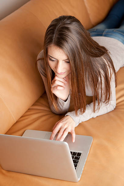 istock Young woman with laptop on sofa 174832027