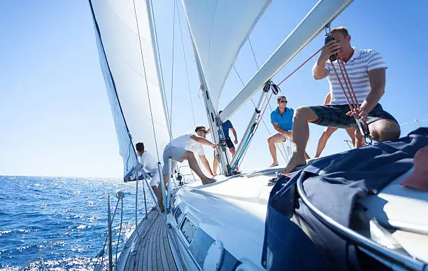 Four Friends run sailboat,pulling the rope, setting up sails