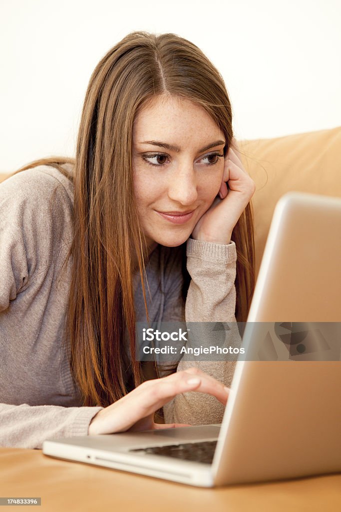 Young woman with laptop on sofa Adult Stock Photo