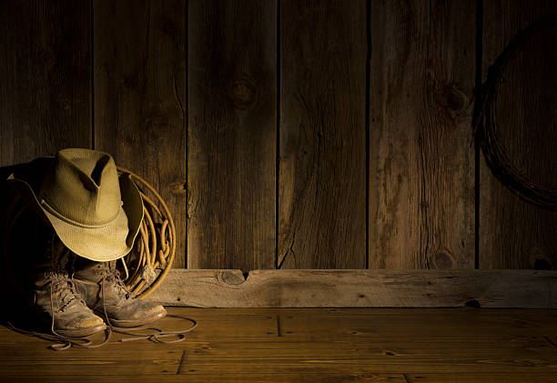istock Western cowboy hat,packer's boots,rope on barn floor-spot lighting 174834137