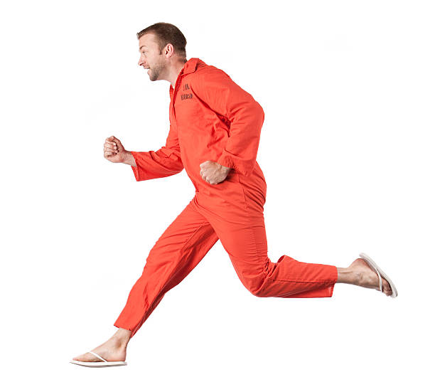 Prison Inmate Running Away An inmate in orange prison coveralls running away and trying to escape. prison escape stock pictures, royalty-free photos & images