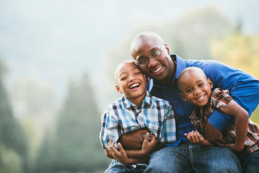 Mid twenties african american father with his two young boys with copy space.