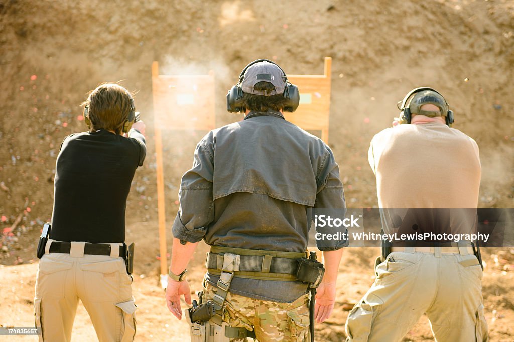 Shooting Range Three adults at shooting range, view from behind. Target Shooting Stock Photo
