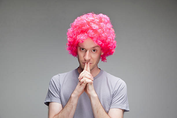 istock young man looking serious with pink wig 174836069