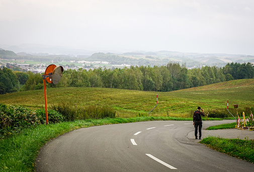 Biei, Japan - Oct 2, 2017. A man walking on road in Biei, Hokkaido, Japan. Biei is a small town surrounded by a picturesque landscape of gently rolling hills and vast fields.