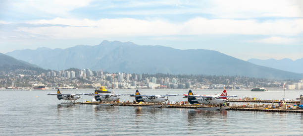 The Harbour Air Launch Pad at Vancouver Harbour Flight Centre, Coal Harbour, Vancouver, Canada. Seaplanes are neatly docked waiting to take passengers out on sightseeing trips. North Vancouver is in the background, with Grouse Mountain behind.