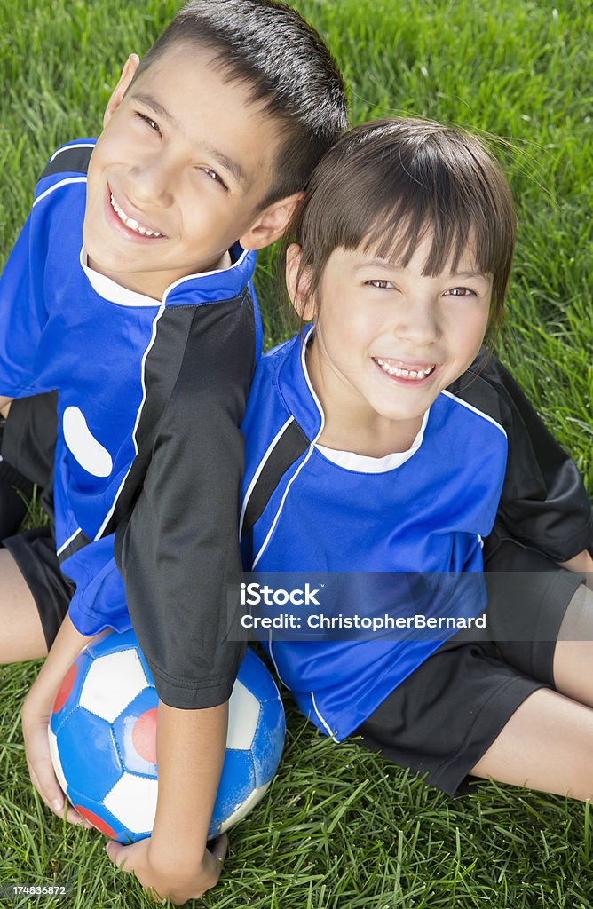 Menino e menina repousando sobre um campo de futebol - Foto de stock de 6-7 Anos royalty-free