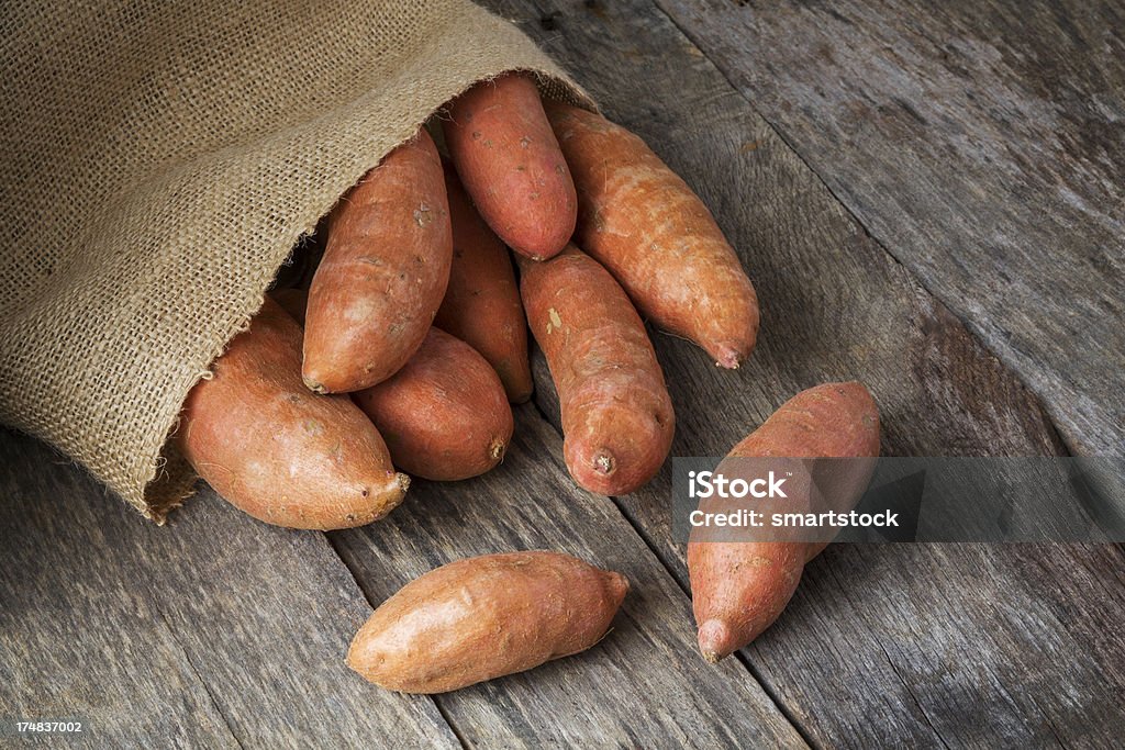 Patates douces renverser du sac de toile de jute - Photo de Patate douce libre de droits