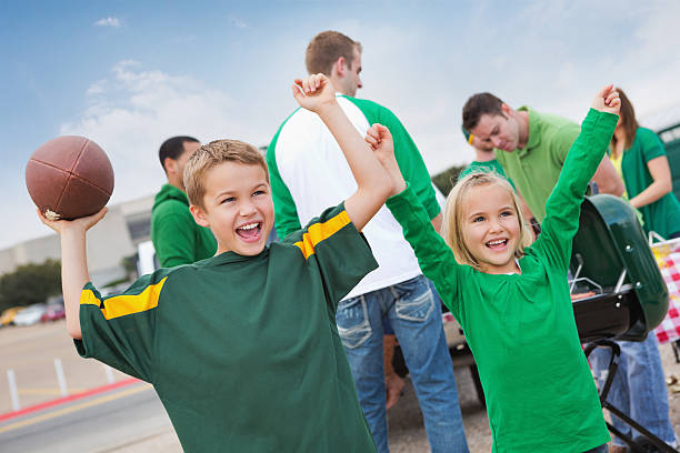 Excited children cheering at tailgate party during college football game Excited children cheering at tailgate party during college football game. people family tailgate party outdoors stock pictures, royalty-free photos & images
