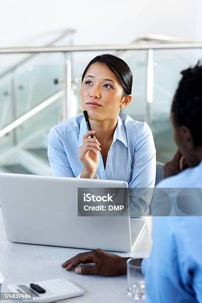 Foto de Pensativa Jovem Mulher De Negócios Em Uma Reunião Asiática e mais fotos de stock de Reunião de negócios