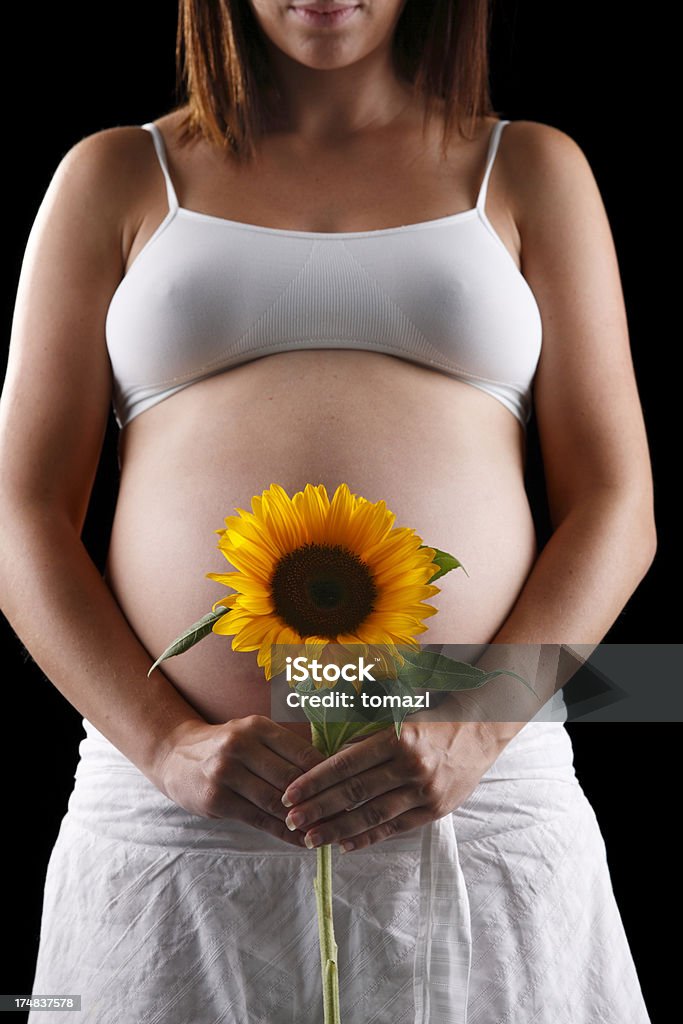 Irreconocible mujer embarazada con flor de sol - Foto de stock de Abdomen libre de derechos