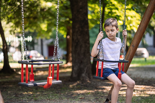 Little boy feeling lonely on the swing