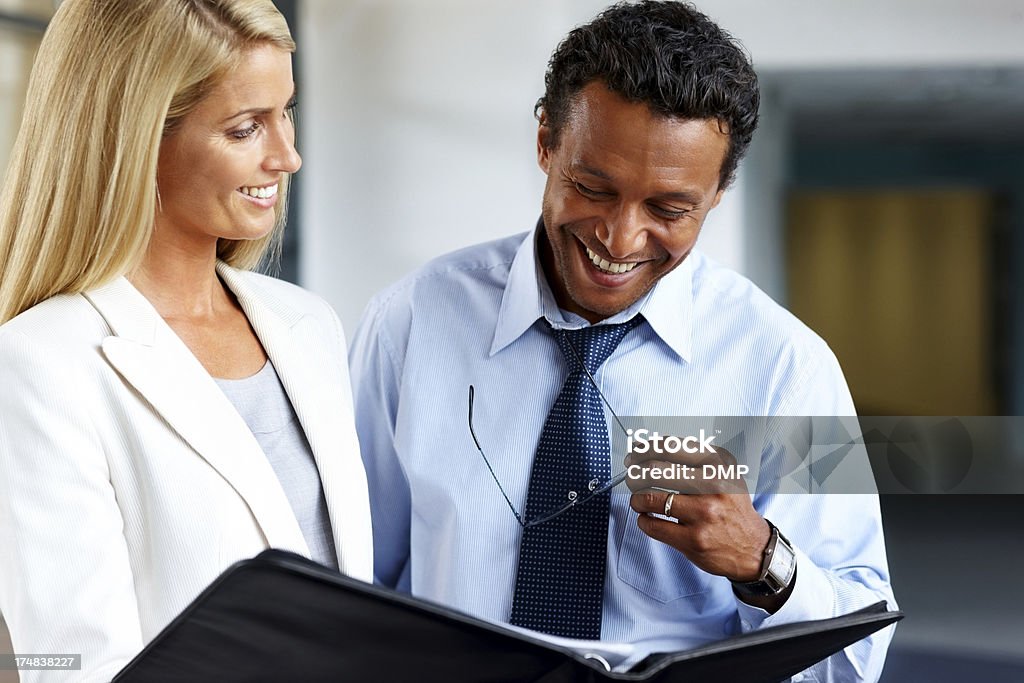 I dirigenti sorridente attraversando report finanziari - Foto stock royalty-free di Abbigliamento formale
