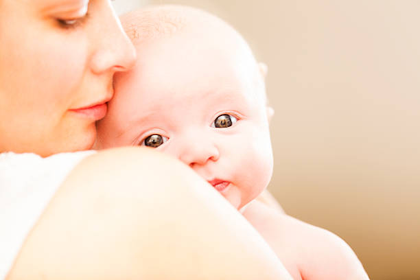 Caring mother smiling while holding her baby boy. 