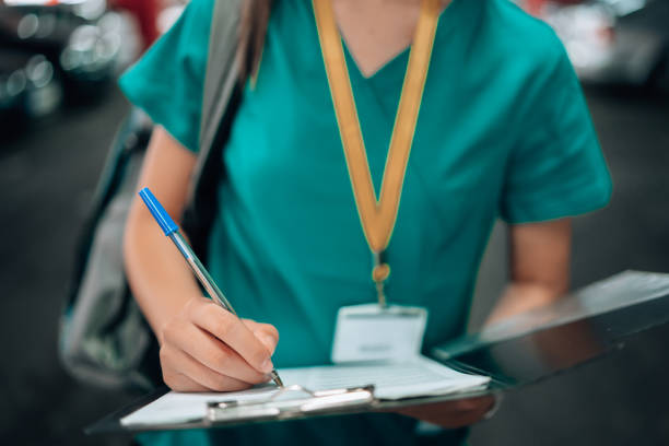 istock Close-up of a young female nurse`s hands writing on a note pad, while standing in a parking lot in scrubs 1748386898