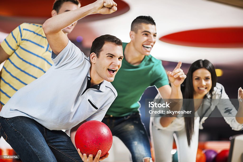 Happy ecstatic friends supporting their bowling team. Group of friends cheering at the bowling alley. 20-24 Years Stock Photo