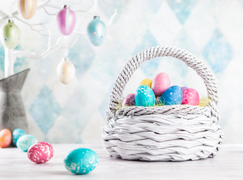 Colourful Easter eggs sitting in a white basket.