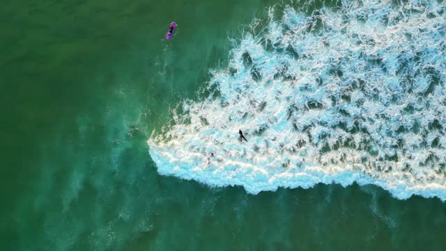 Seen from above, surfers paddled with the waves breaking, leaving a trail of foam, Cascais,Portugal- top down, drone shot