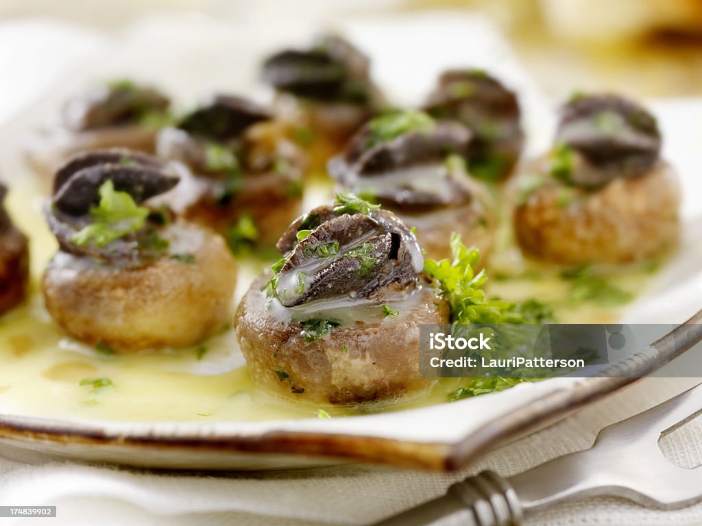 Escargot Stuffed Mushrooms "Escargot Stuffed Mushrooms with a Herb Butter, White Wine and Garlic Sauce with Fresh Parsley -Photographed on Hasselblad H3D2-39mb Camera" Edible Mushroom Stock Photo