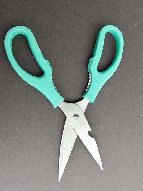 istock Selective focus of an open scissor with green handle isolated on black background 1748406145