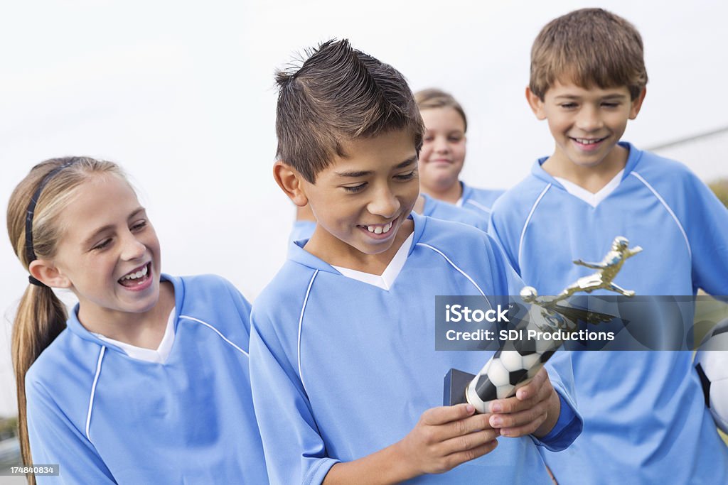 Young soccer player mirando a su galardonada trophy - Foto de stock de Trofeo libre de derechos