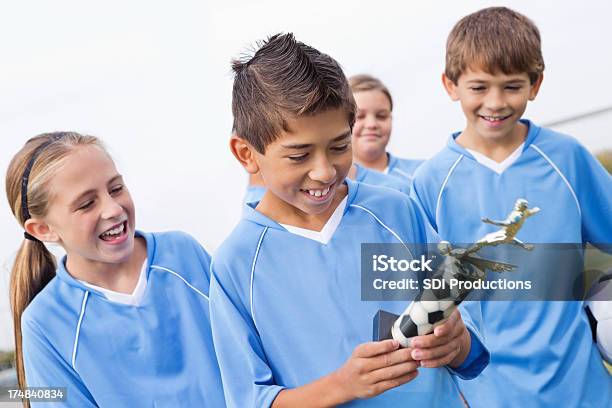 Young Soccer Player Mirando A Su Galardonada Trophy Foto de stock y más banco de imágenes de Trofeo