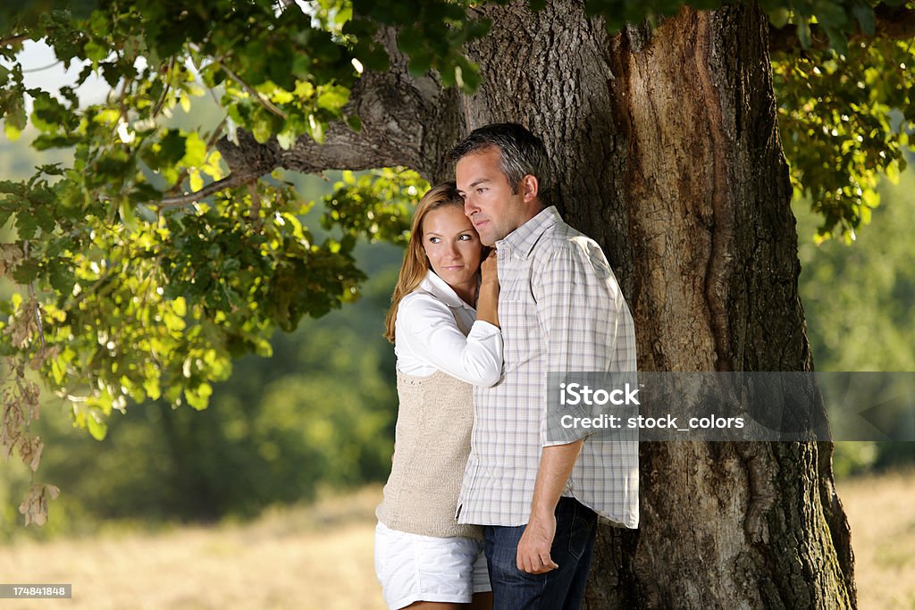 Coppia in posa vicino albero - Foto stock royalty-free di 25-29 anni