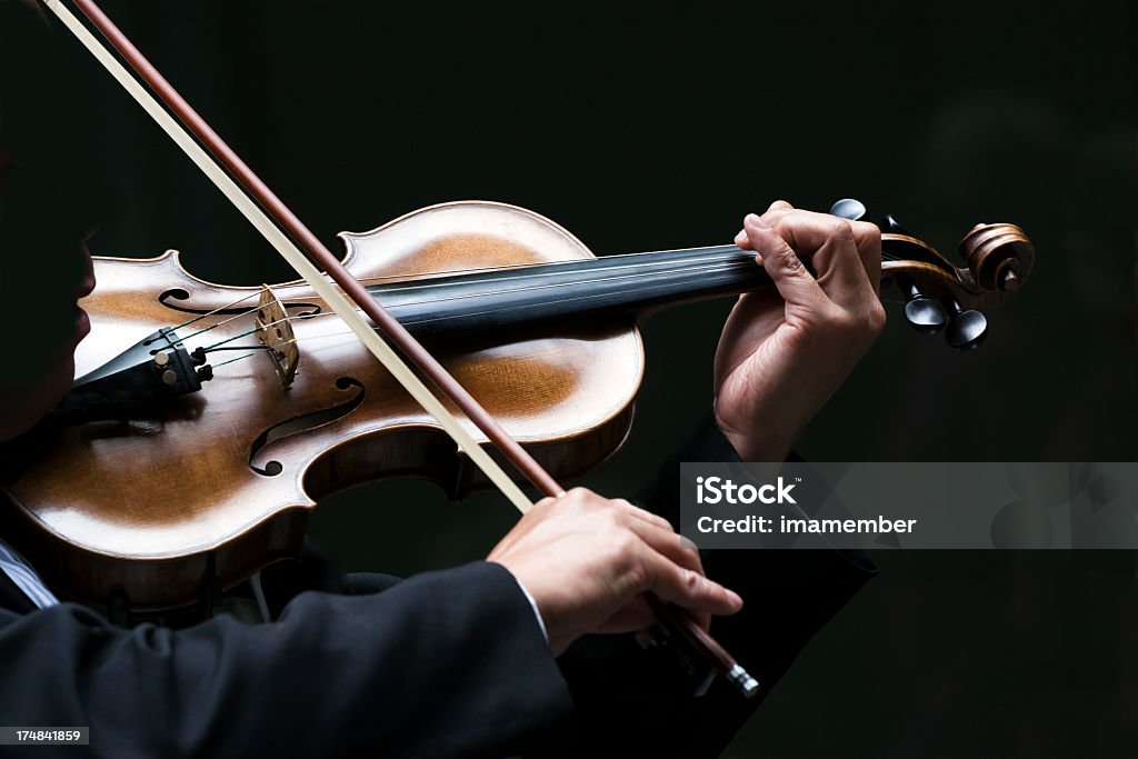 Male Violinist against dark background, copy space Closeup male violinist playing on violin against dark background, full frame horizontal composition with copy space Artist Stock Photo