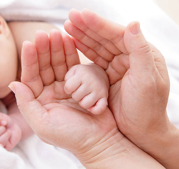 istock mother holding baby hand 174842046