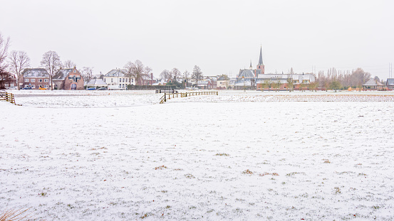 A snow-covered lawn in the polder with a village in the background.