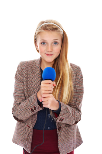 Portrait of a confident young reporter holding microphone against white background
