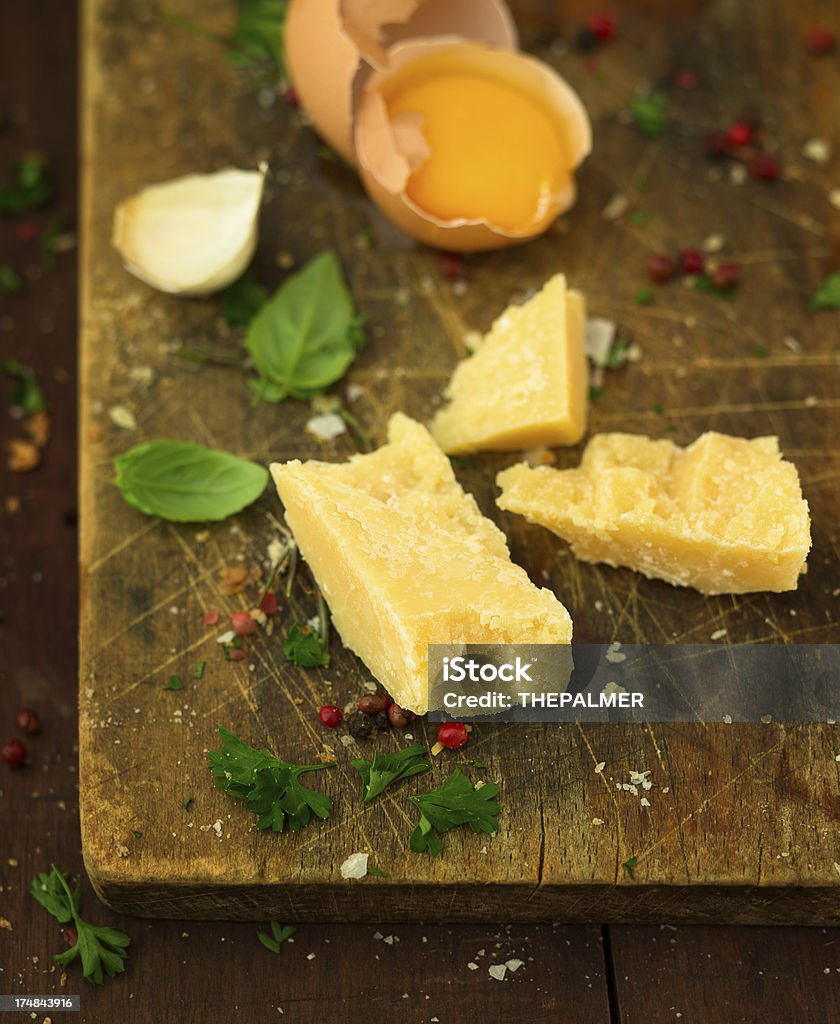 parmesan cheese pieces of parmesan cheese, basil leave, pepper and salt over an aged cutting board. Aging Process Stock Photo