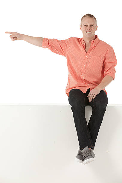 istock Man sitting on the ledge of a wall and pointing 174844107