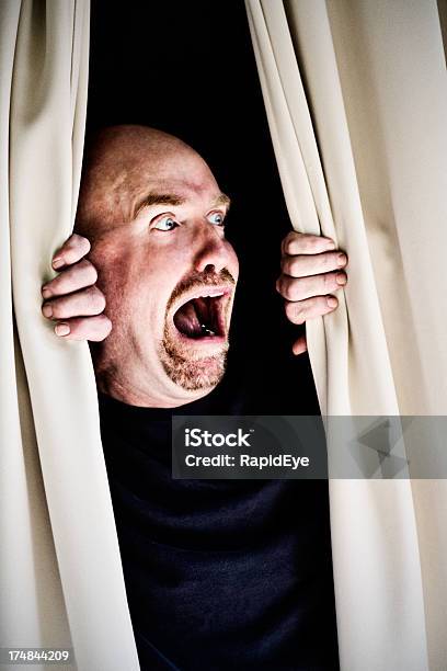 Terrified Man Looks Through Curtains In Horror Major Trouble Here Stock Photo - Download Image Now