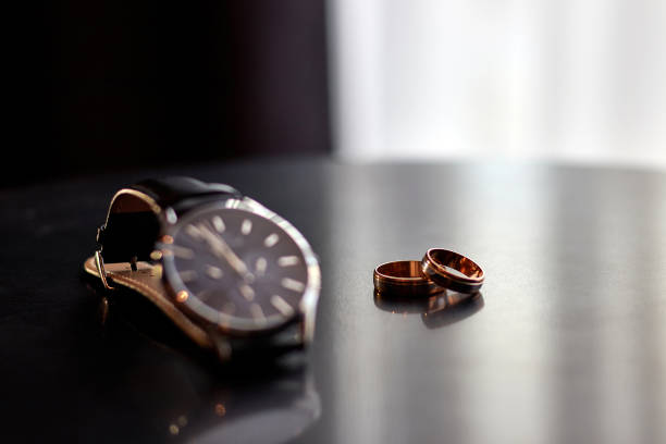istock Clock and two wedding gold wedding rings on the table. Preparing for the wedding. 1748446699