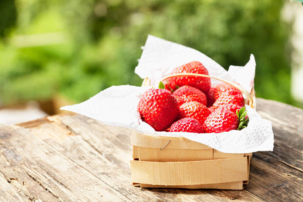 strawberries in wooden basket, standing on weathered wooden background, outdoors in summer, in the garden, 