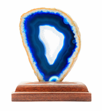 Slice of blue agate crystal with wood stand on white background