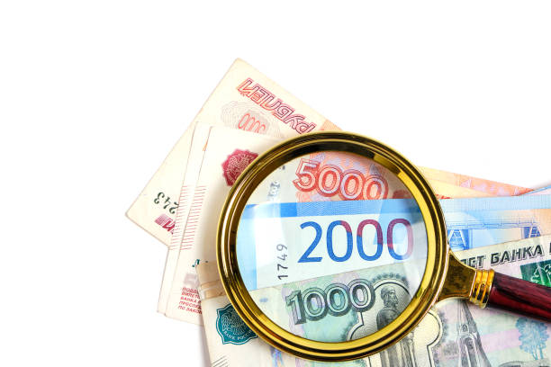 istock Magnifying glass and Russian ruble banknotes in denominations one, two and five thousand rubles white background. 1748452390