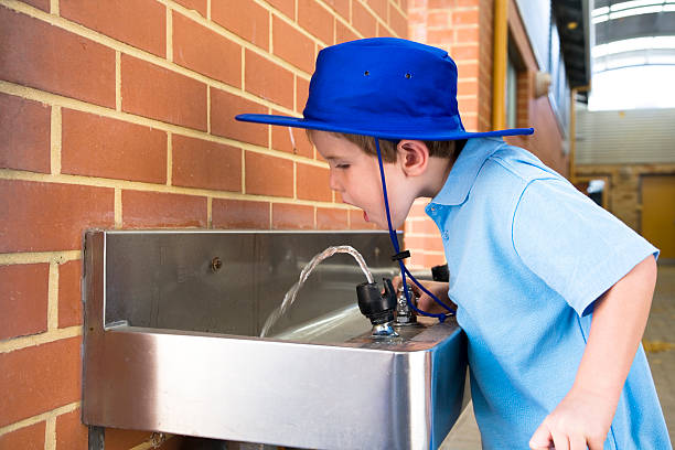 A five year old Australian school boy having a drink from the water fountain.